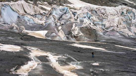 A team member of the Swiss Federal Institute of Technology passes the Rhone Glacier covered by sheets near Goms, Switzerland. A top glacier watcher has warned that a warm early summer and a heat wave last week could have caused severe glacier melt across Switzerland.(AP)